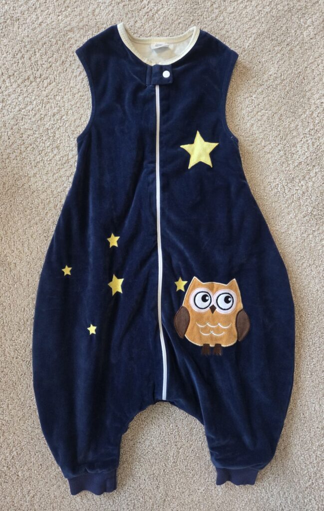 Top-down view of a dark blue 'feet-free' velvet toddler sleep sack with a cute owl and yellow stars