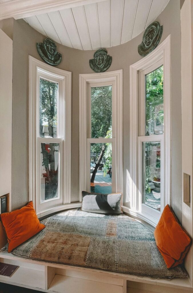 An inviting reading nook shaped like a half-circle with a sitting cushion to fit, a few throw pillows, and three large windows