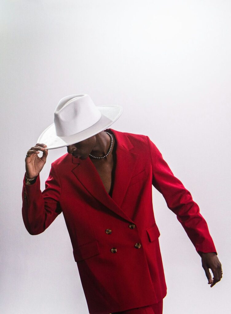 A man in Moscow poses in a red suit with no shirt underneath and holds the tip of his white hat