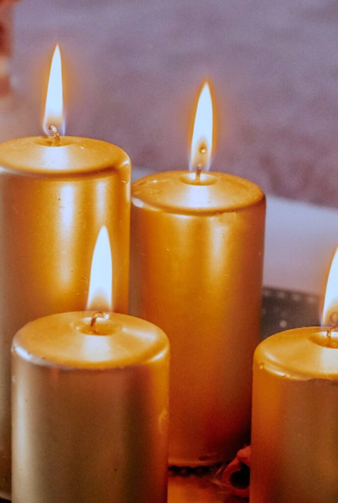 Close-up photo of several lit gold-coloured pillar candles